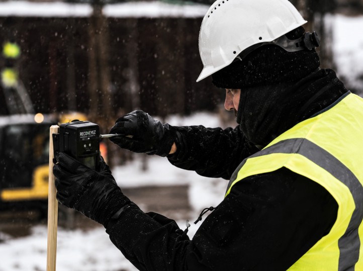 Worker installing a Reconeyez wireless security sensor at a construction site