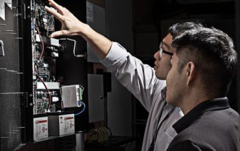 Technicians inspecting a physical access control controller panel