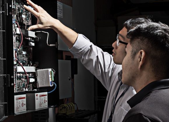 Technicians inspecting a physical access control controller panel