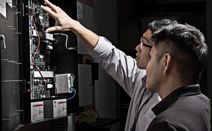 Technicians inspecting a physical access control controller panel