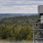 Teledyne FLIR Ranger R10-3DX counter-drone radar mounted on a surveillance tower overlooking a forest