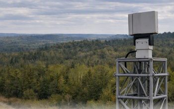 Teledyne FLIR Ranger R10-3DX counter-drone radar mounted on a surveillance tower overlooking a forest