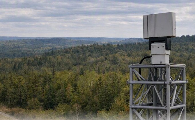 Teledyne FLIR Ranger R10-3DX counter-drone radar mounted on a surveillance tower overlooking a forest